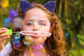 Portrait of a happy little curly girl playing with soap bubbles on a summer nature, wearing a blue ears of tiger Royalty Free Stock Photo