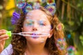 Portrait of a happy little curly girl playing with soap bubbles on a summer nature, wearing a blue ears of tiger Royalty Free Stock Photo