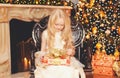 Portrait happy little girl child opens gift box near christmas tree with garland lights and fireplace at home Royalty Free Stock Photo