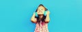 Portrait of happy little girl child in wireless headphones listening to music on blue background, blank copy space for advertising Royalty Free Stock Photo