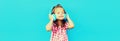 Portrait of happy little girl child in wireless headphones listening to music on blue background, blank copy space for advertising Royalty Free Stock Photo