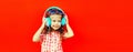 Portrait of happy little girl child in wireless headphones listening to music on red background, blank copy space for advertising Royalty Free Stock Photo