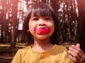 Portrait of happy little girl eating red apple outdoors in summer. Childhood happiness Royalty Free Stock Photo