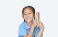 Portrait happy little girl in school uniform holding color pencils over white background. Education and school concept Royalty Free Stock Photo