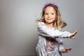 Portrait of happy little girl  in white dress and purple wreath on gray isolated background Royalty Free Stock Photo