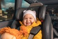 Portrait of a happy little kid sitting in a child seat in the back seat of a car. The concept of safe trip and child