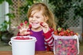 Portrait of happy little preschool girl eating healthy strawberries and raspberries. Smiling child with ripe berries Royalty Free Stock Photo