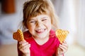 Portrait of happy little preschool girl holding fresh baked heart waffle. Smiling hungry toddler child with sweet