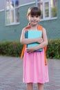 Portrait of happy school girl child with backpack and notebooks isolated on a school background