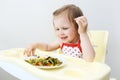 Portrait of happy little 2 years girl eating fish with vegetable