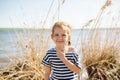 Portrait of a happy lively little girl by the lake at spring, dry grass around