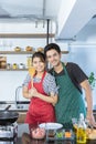 Portrait of happy lovely young Asian couple in love with casual clothes in modern kitchen, is smiling, looking at camera and