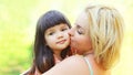 Portrait happy loving mother kissing child outdoors in summer Royalty Free Stock Photo