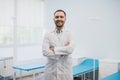 Portrait of a happy male doctor standing with arms crossed at medical office Royalty Free Stock Photo