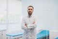 Portrait of a happy male doctor standing with arms crossed at medical office Royalty Free Stock Photo