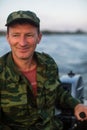 Portrait of a happy man in camouflage driving a motor boat. Royalty Free Stock Photo