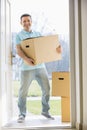 Portrait of happy man carrying cardboard box while entering new home Royalty Free Stock Photo