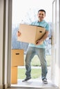 Portrait of happy man carrying cardboard box while entering new home Royalty Free Stock Photo