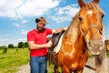 Portrait of happy man in cowboy hat saddling horse Royalty Free Stock Photo