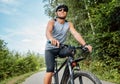 Portrait of happy man dressed in cycling clothes, helmet and sunglasses riding a bicycle on the out-of-town bicycle path. Active Royalty Free Stock Photo