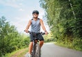 Portrait of happy man dressed in cycling clothes, helmet and sunglasses riding a bicycle on the out-of-town bicycle path. Active Royalty Free Stock Photo