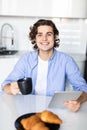 Portrait of happy man eat at breakfast and using digital tablet in kitchen at home Royalty Free Stock Photo