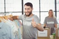 Portrait of happy man gesturing thumbs up while selecting clothes Royalty Free Stock Photo