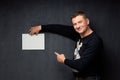 Portrait of happy man holding paper sheet and pointing at it Royalty Free Stock Photo