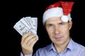 Portrait of happy man in Santa hat with US dollars in hand on black background