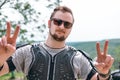 Portrait of a happy man, Shows on fingers peace. motorcycle equipment, jacket turtle, body armor. Close. In the background a