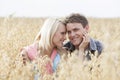 Portrait of happy man sitting with romantic woman amidst field