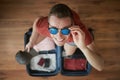 Portrait of happy man with sunglasses while packing suitcase Royalty Free Stock Photo