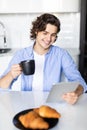 Portrait of happy man eat at breakfast and using digital tablet in kitchen at home Royalty Free Stock Photo