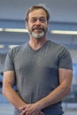 portrait of happy man 50-55 years old with beard in gray T-shirt on blurred background of railway station, vertical photo. Royalty Free Stock Photo