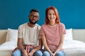 Portrait of happy married interracial diverse couple smiling at camera while sitting together on bed Royalty Free Stock Photo