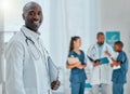 Portrait of a happy mature african american male doctor holding a folder working at a hospital with colleagues. Expert Royalty Free Stock Photo