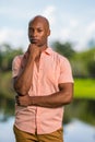 Portrait happy mature African American man wearing a pink button summer shirt and looking at camera outdoor. Man with hand Royalty Free Stock Photo