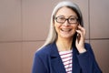 Portrait of a happy mature business woman wearing eyeglasses and classic wear talking on mobile phone and smiling while Royalty Free Stock Photo