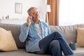 Cheerful mature man talking on cellphone sitting on sofa Royalty Free Stock Photo