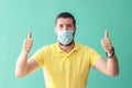 Portrait of happy mature man with protective face mask smiling with thumbs up suggesting safety and prevention for coronavirus