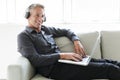 Portrait of happy mature man using laptop lying on sofa in house Royalty Free Stock Photo