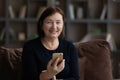 Portrait of happy mature 60s woman holding mobile phone Royalty Free Stock Photo