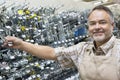 Portrait of a happy mature salesperson holding metallic equipment in hardware store