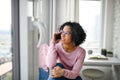 Portrait of happy mature woman making a phone call indoors, looking out of window. Royalty Free Stock Photo