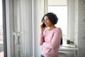 Portrait of happy mature woman making a phone call indoors, looking out of window. Royalty Free Stock Photo