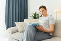 Portrait of a happy mature woman relaxing on couch and reading a book in a modern house Royalty Free Stock Photo