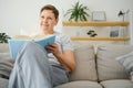 Portrait of a happy mature woman relaxing on couch and reading a book in a modern house Royalty Free Stock Photo