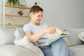 Portrait of a happy mature woman relaxing on couch and reading a book in a modern house Royalty Free Stock Photo