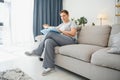 Portrait of a happy mature woman relaxing on couch and reading a book in a modern house Royalty Free Stock Photo