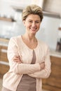 Portrait of happy mature woman standing with arms crossed at home Royalty Free Stock Photo